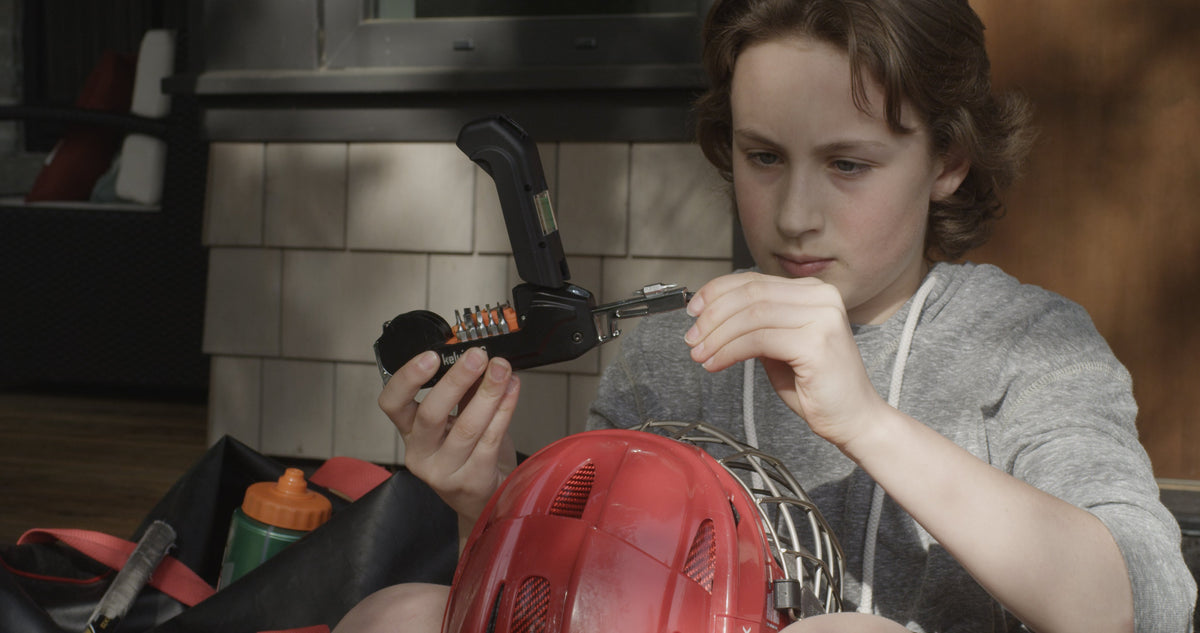 A teenager fixing a bike helmet at home with a Kelvin multitool