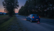 Car on the shoulder at dusk with hazard lights and a warning triangle